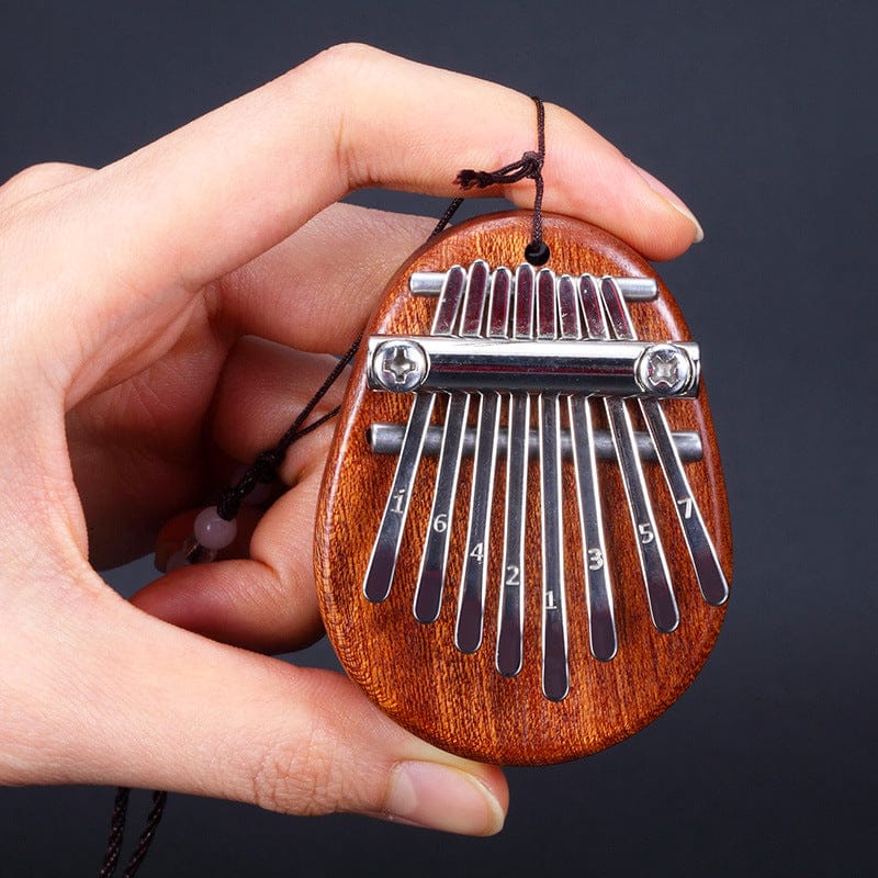 Hand holding wooden kalimba with numbered metal tines, portable thumb piano for healing music