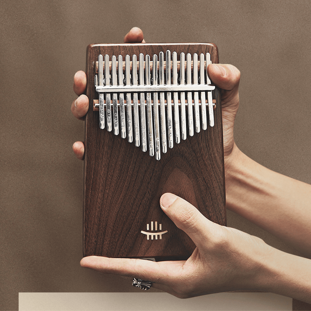 Hand holding wooden kalimba with metal tines, ideal for healing music and relaxation