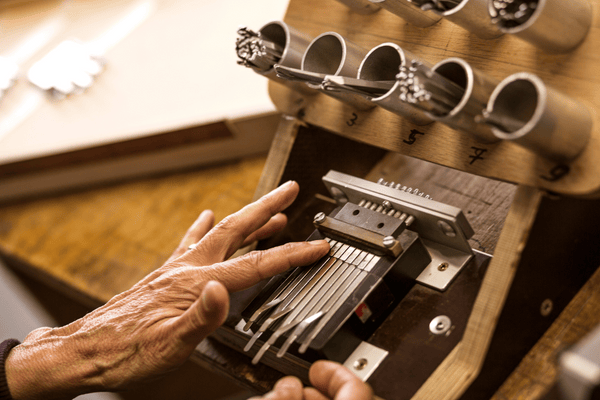 Hand playing kalimba with metal tines, wooden body, and tuning pegs — soothing musical instrument for relaxation