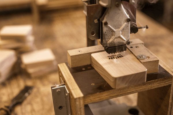 Wooden kalimba being engraved with laser in workshop, showcasing handcrafted musical instrument detail