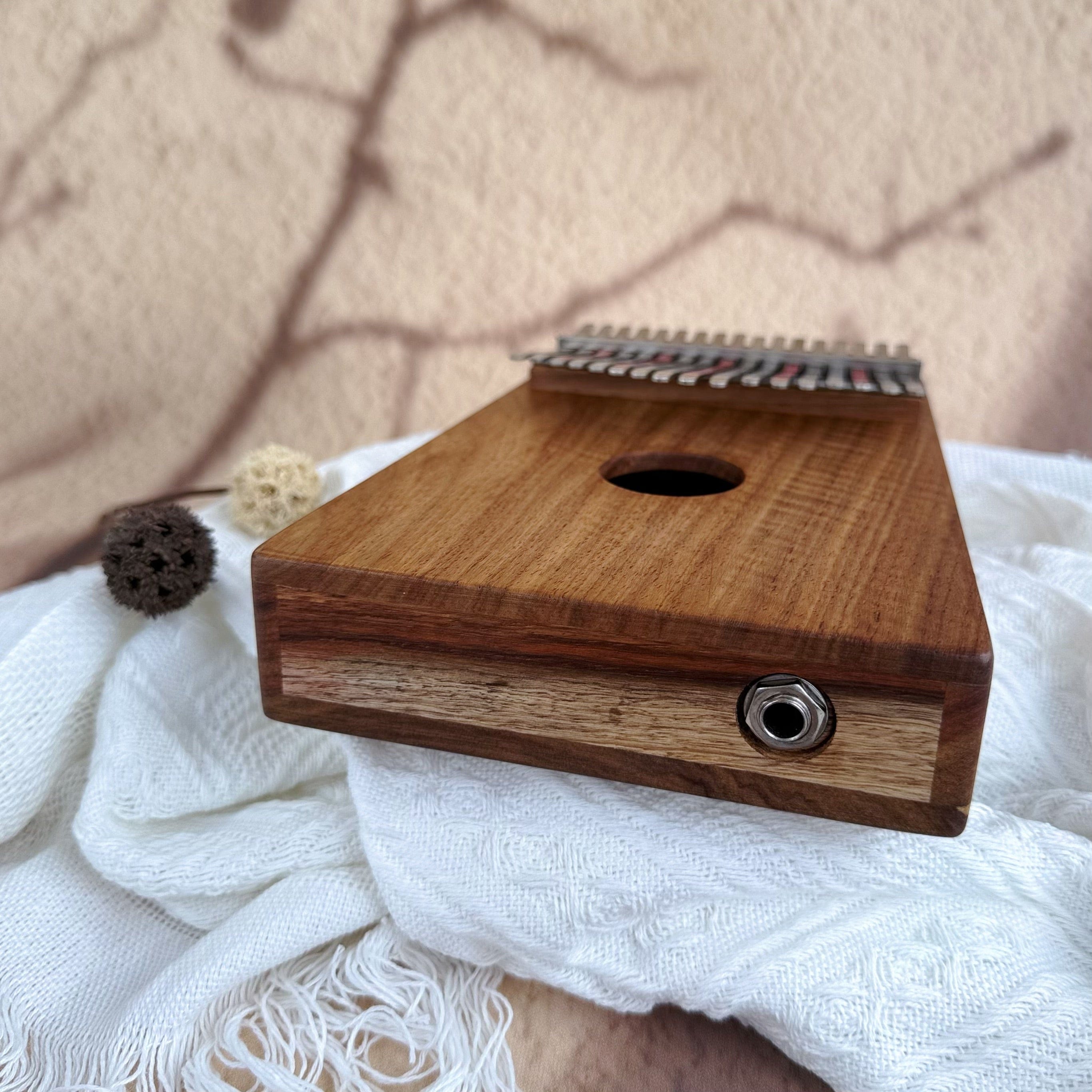 Wooden kalimba thumb piano with metal tines, resting on white fabric, ideal for healing music and meditation