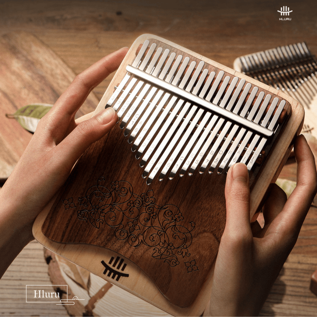 Hands holding a wooden kalimba with engraved floral design and metal tines, ideal for healing music and relaxation.