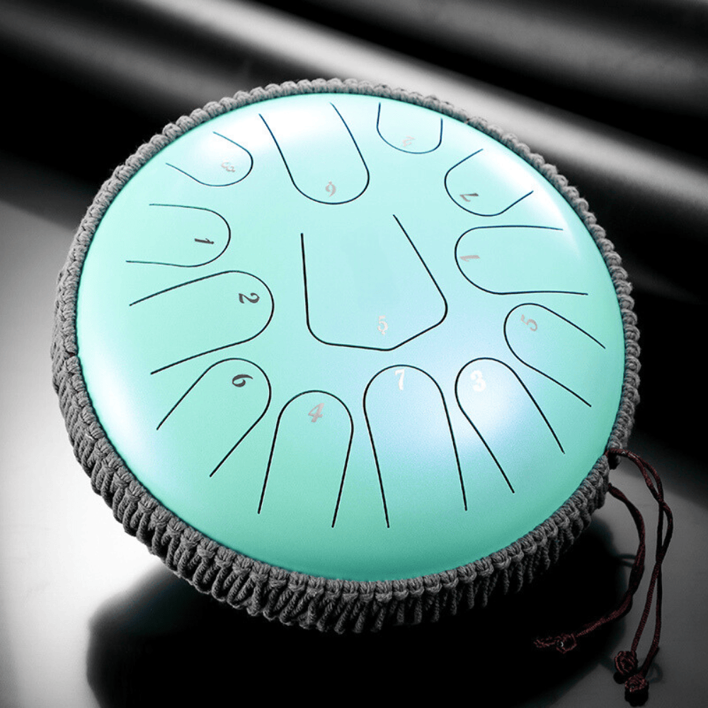 Mint green steel tongue drum with numbered notes, nestled in gray woven case, ideal for meditation and healing sound therapy.
