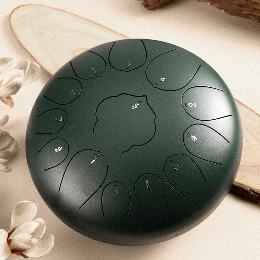 Dark green handpan with numbered tone fields, styled with wood slice and white flowers for serene ambiance