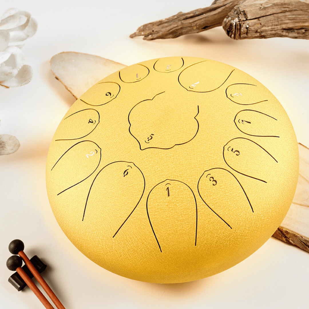 Golden handpan drum with numbered notes, mallets, and natural wood accents for healing sound therapy