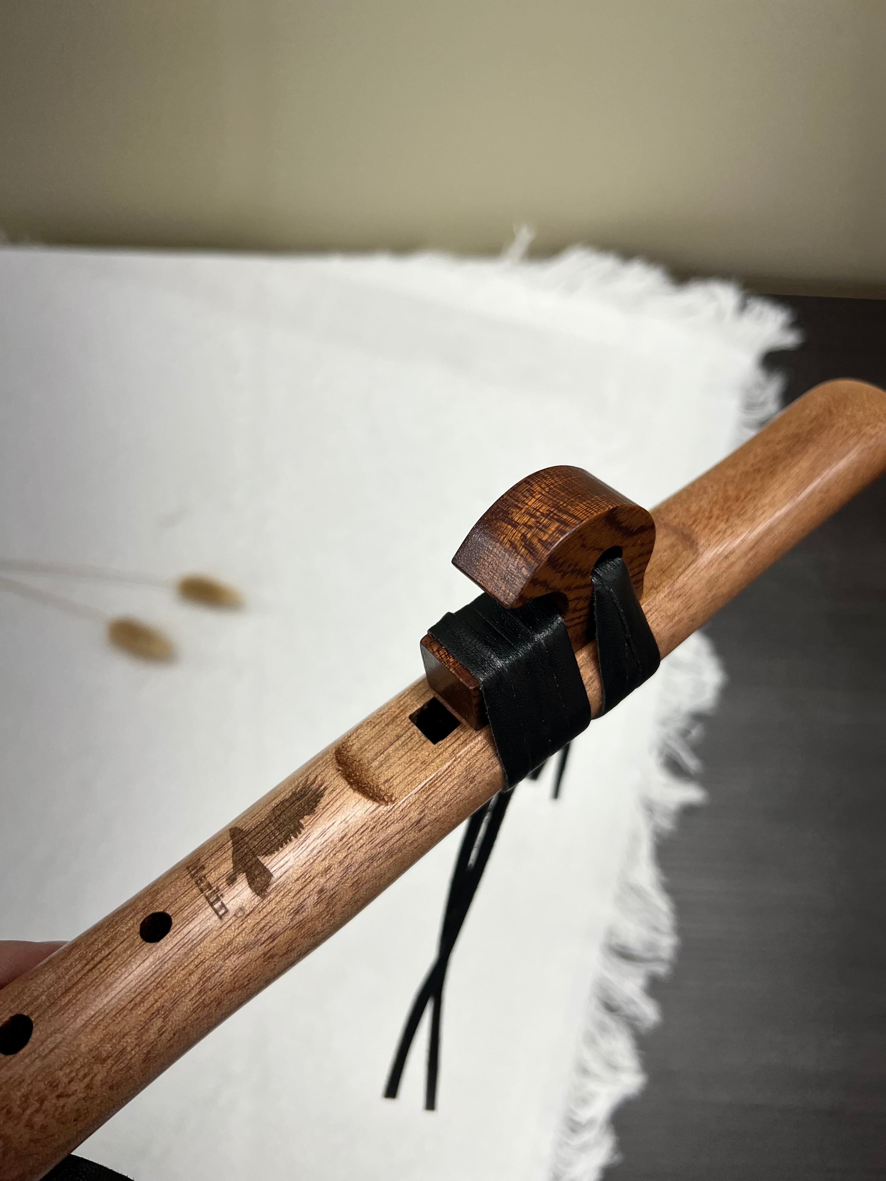 Handcrafted wooden flute with engraved bird design and leather strap, ideal for healing music and meditation.