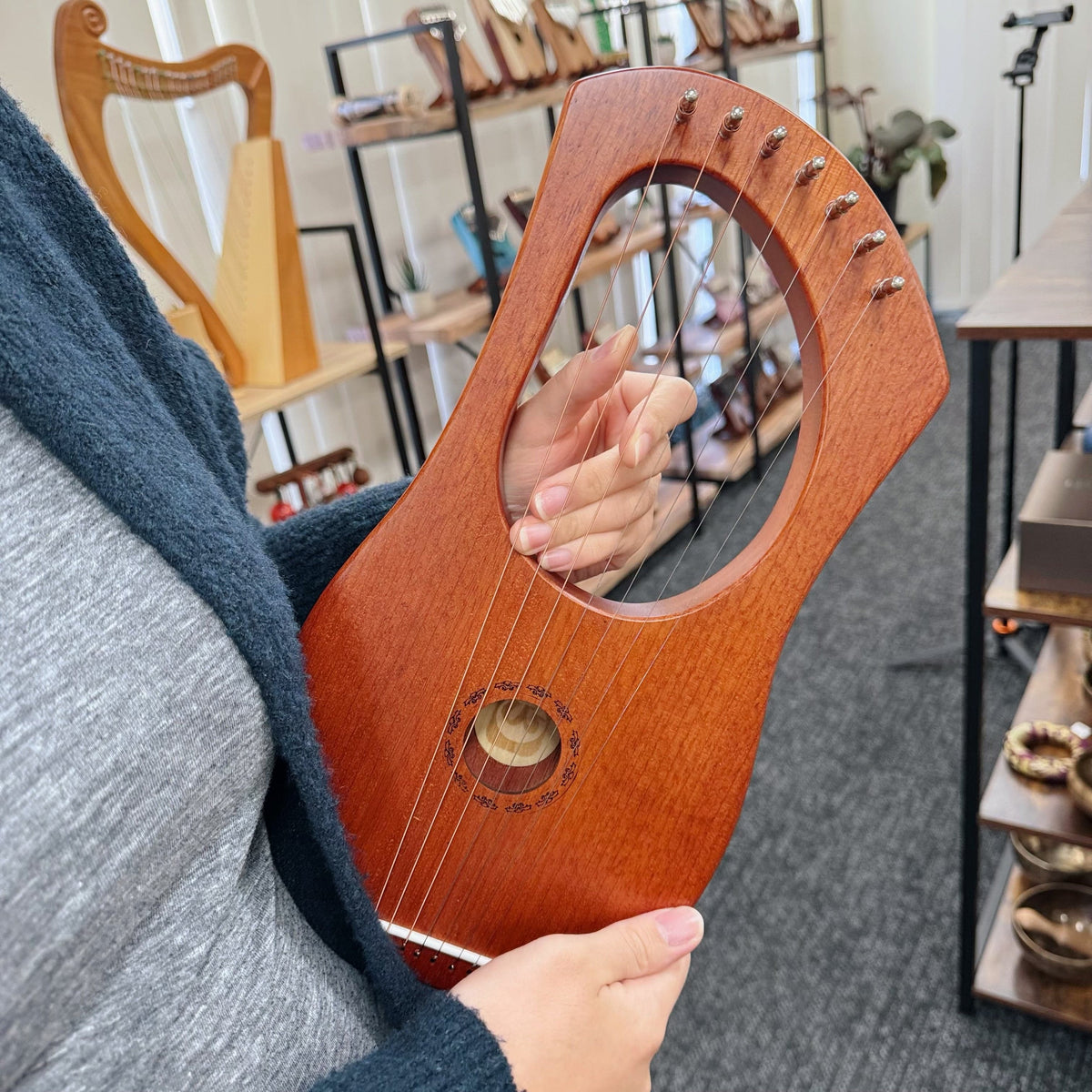 Hand playing wooden lyre harp with strings, in music shop setting