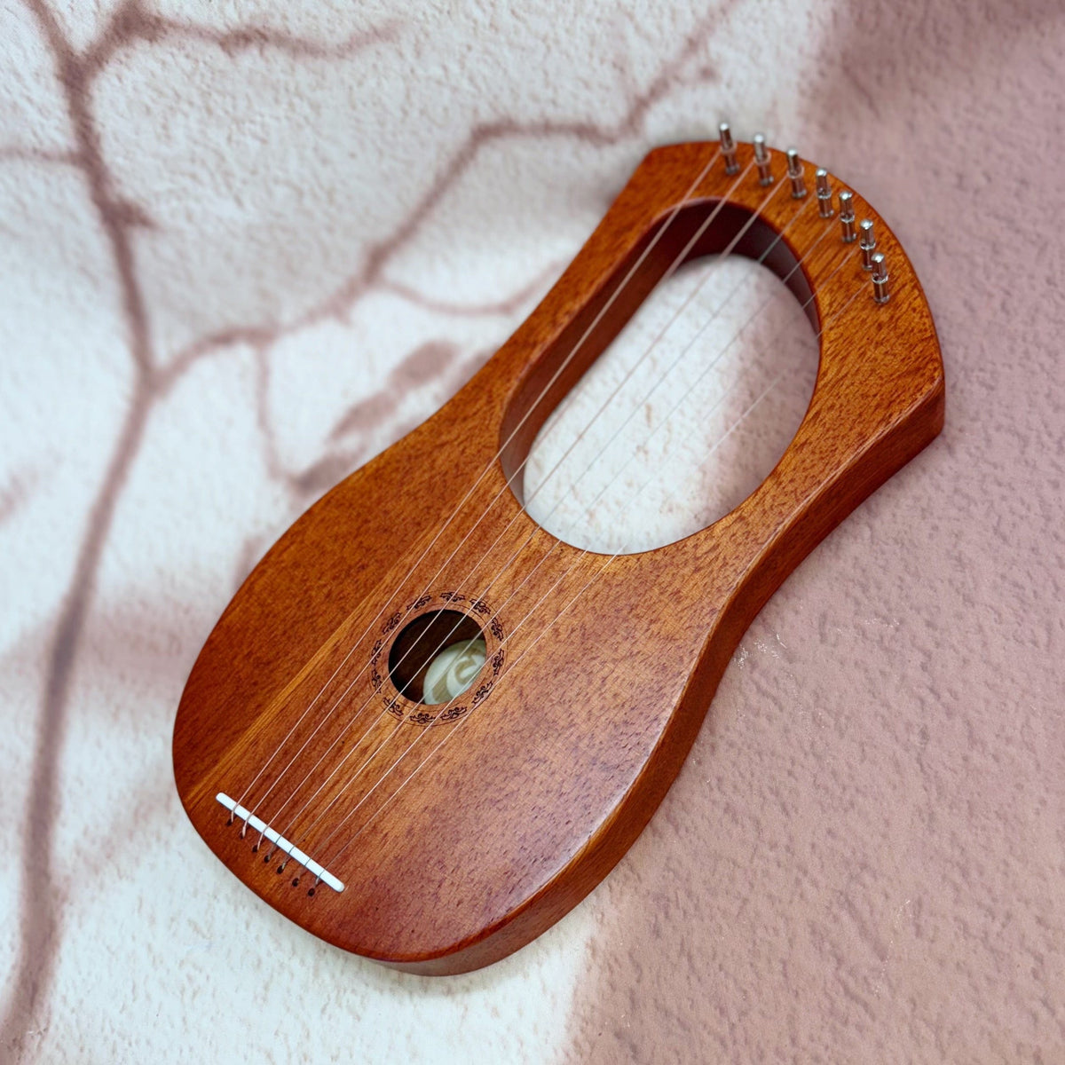 Wooden lyre harp with strings, resting on soft textured surface, ideal for healing and meditation music.