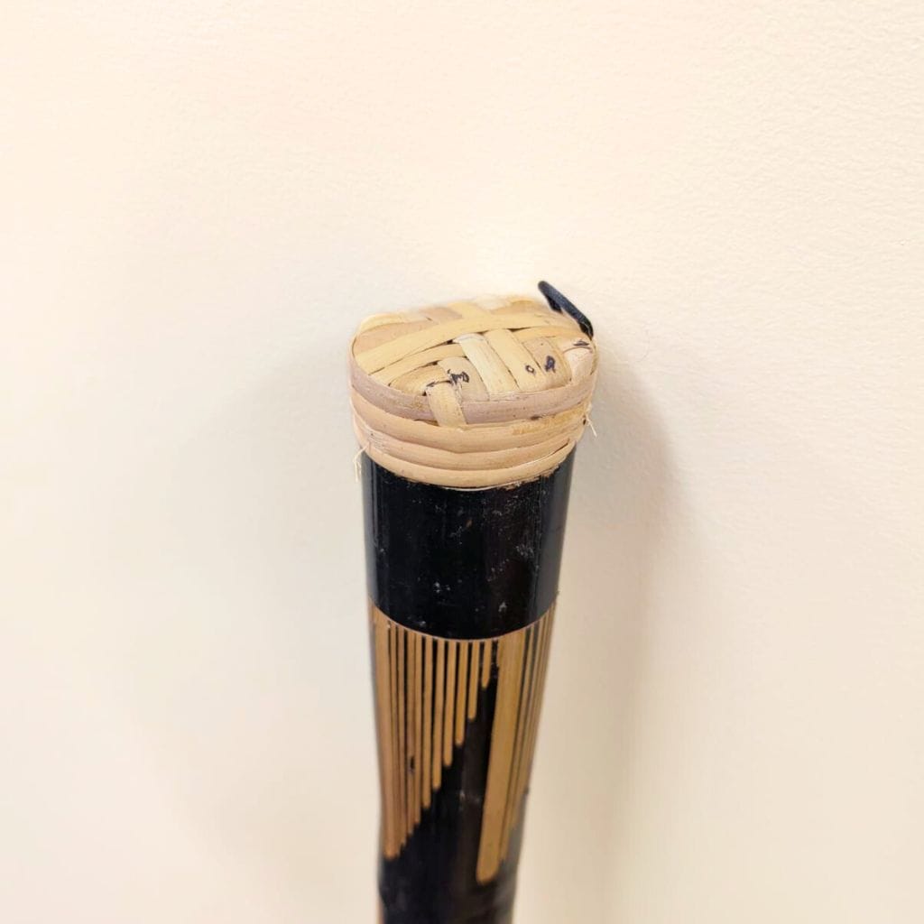 Handcrafted bamboo musical instrument with woven top and black body, ideal for healing sound therapy