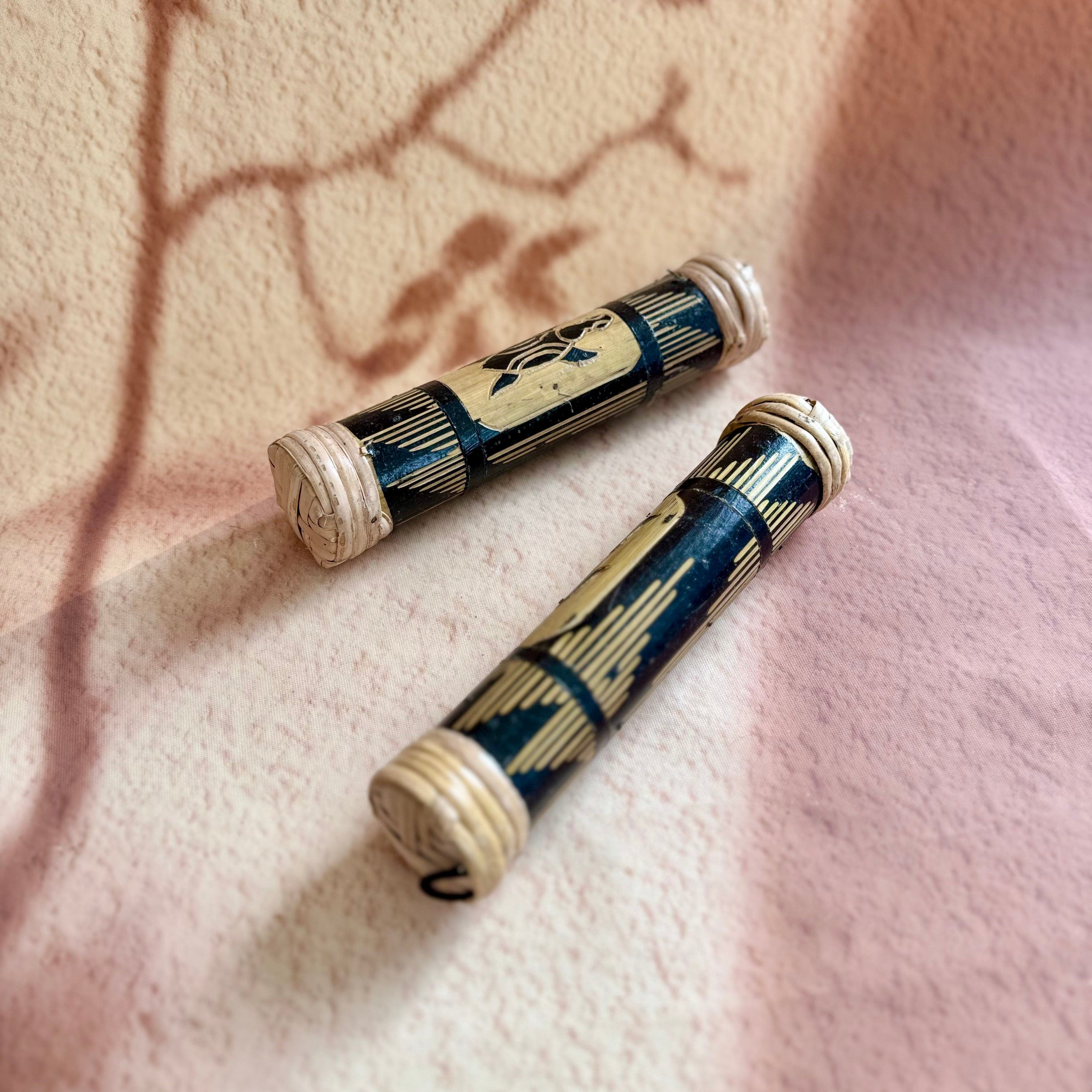 Handcrafted bamboo musical instruments with intricate carvings, resting on soft patterned fabric