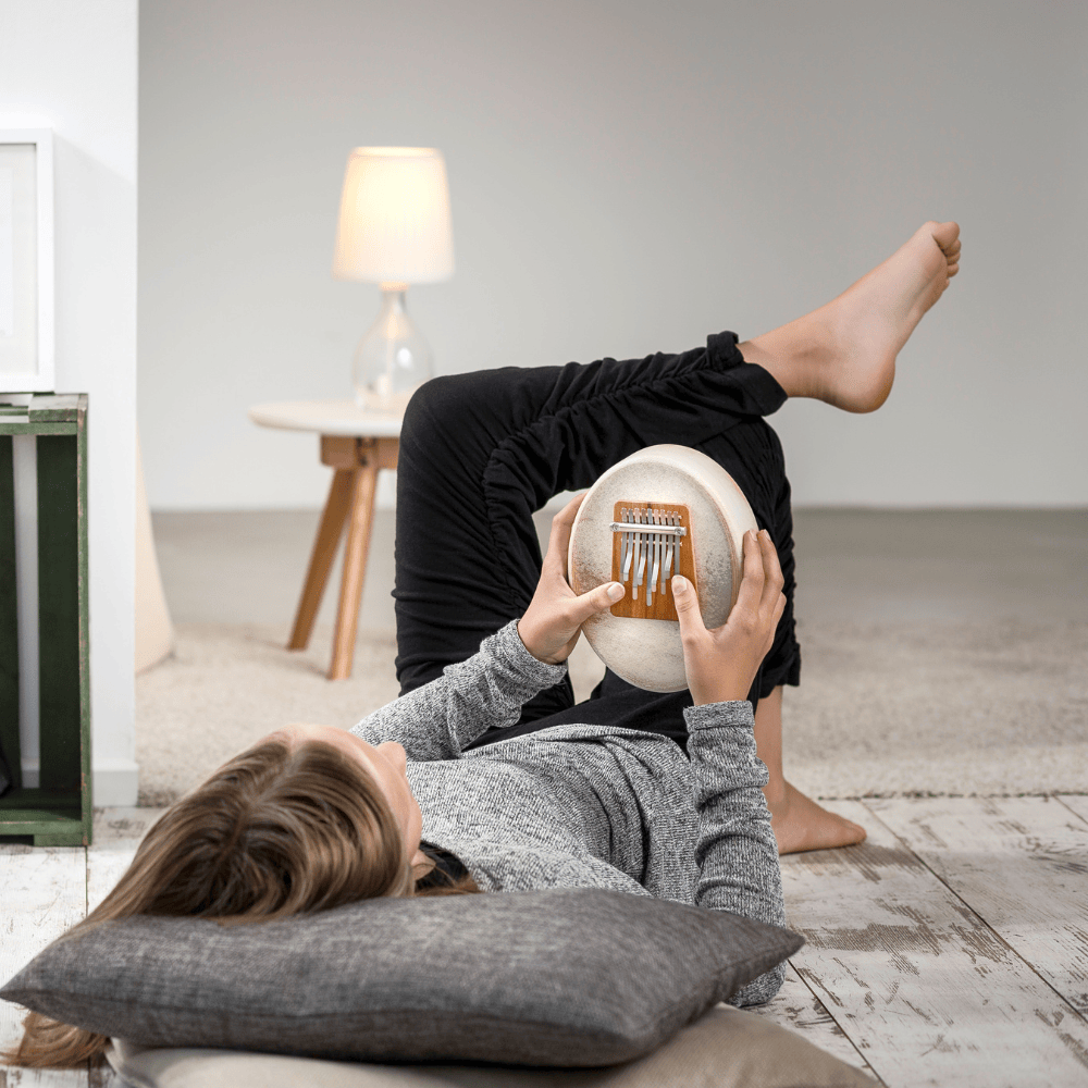 Woman relaxing on floor playing kalimba, healing musical instrument for peace and creativity