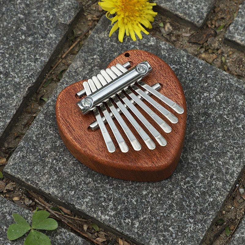 Heart-shaped kalimba thumb piano on stone with dandelion, healing musical instrument