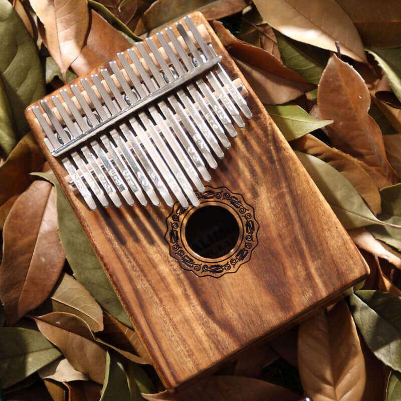 Wooden kalimba thumb piano with metal tines, nestled in autumn leaves, ideal for healing music and mindfulness.