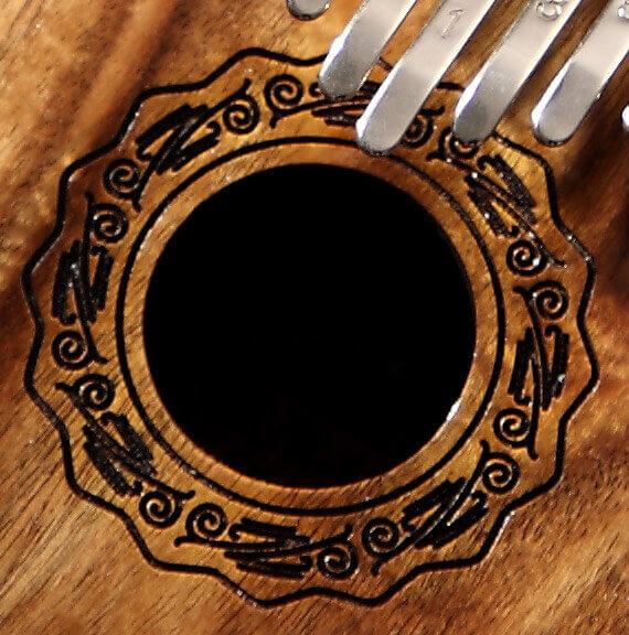 Handcrafted wooden kalimba with intricate carved soundhole and metal tines, ideal for healing music and meditation.