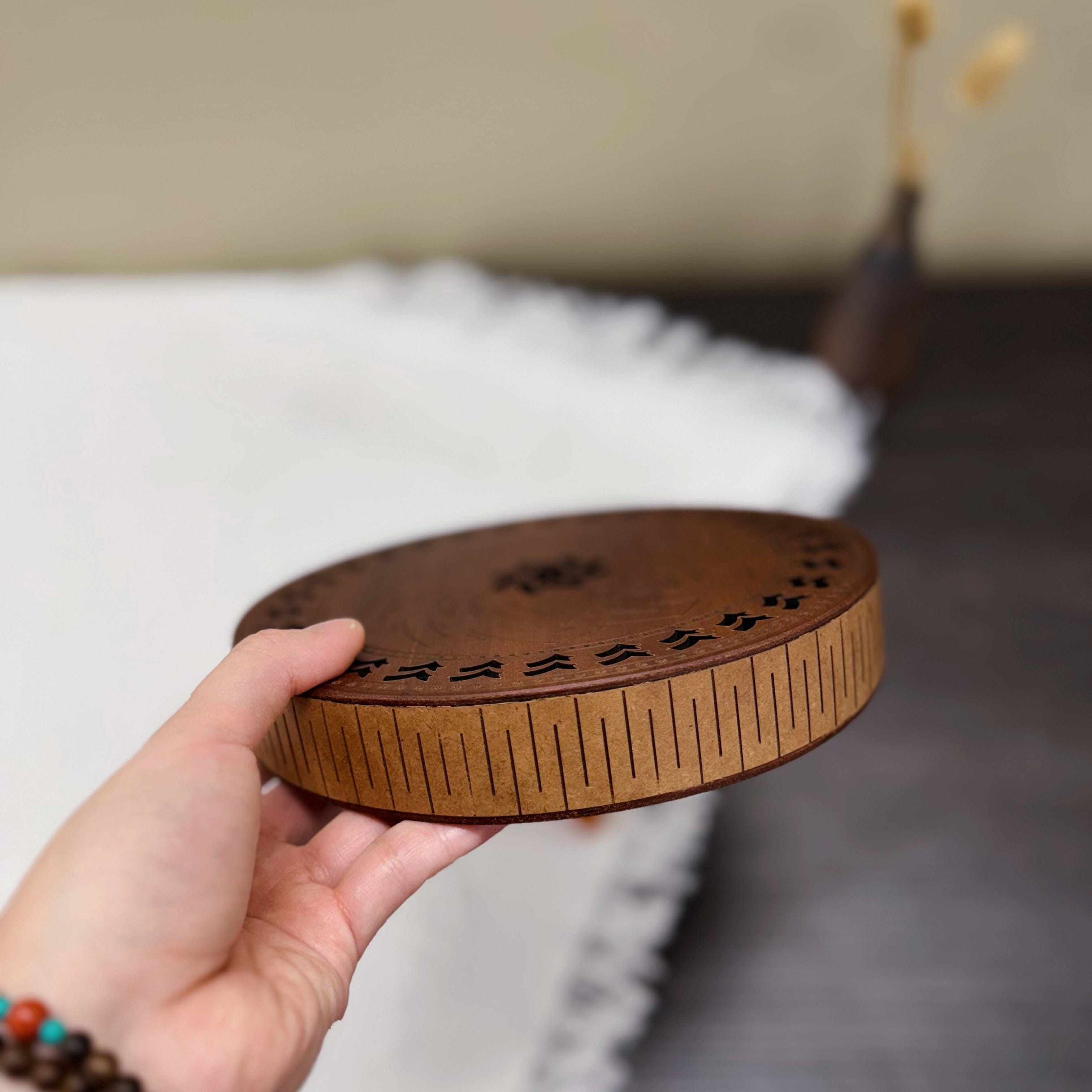 Hand holding wooden tongue drum with engraved notes, ideal for meditation and healing sound therapy.