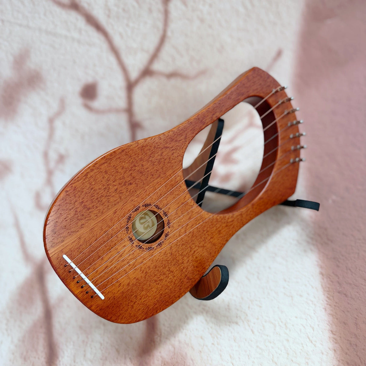 Wooden lyre harp with strings, resting on soft textured surface, ideal for healing and meditation music
