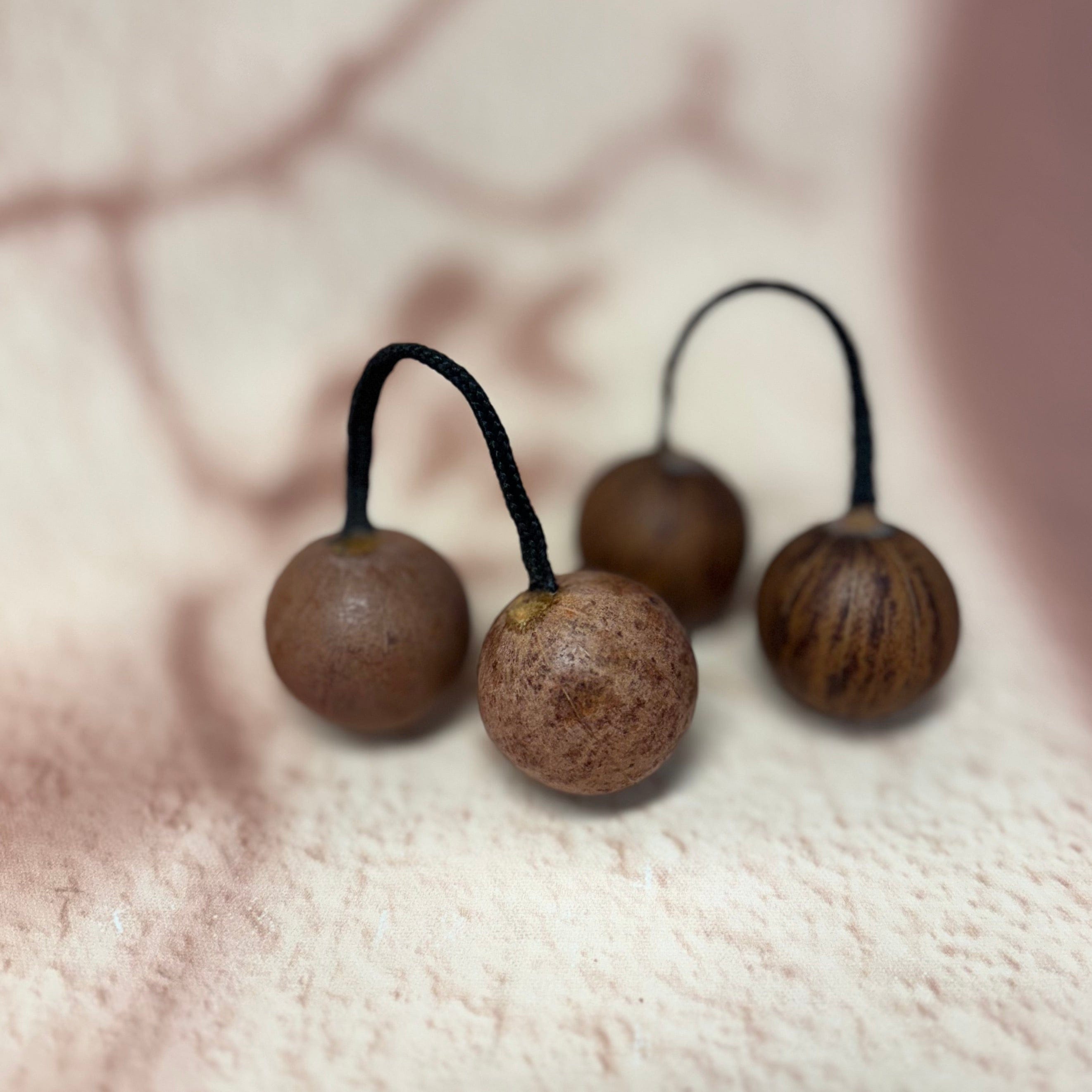 Handcrafted wooden kalimba thumb picks with black cord loops, natural grain texture on soft background