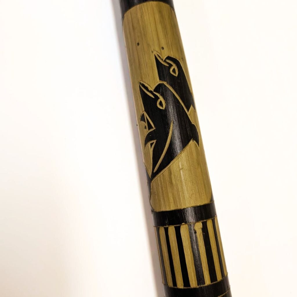 Bamboo didgeridoo with carved wolf design, natural wood texture and black accents