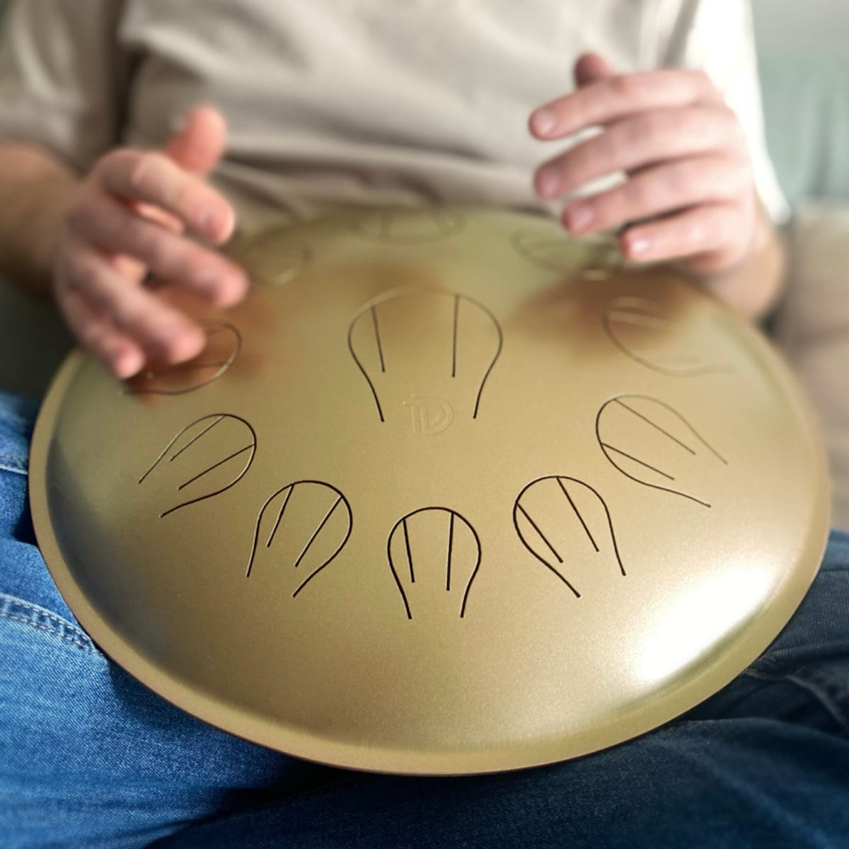Person playing golden handpan drum, healing musical instrument for peace and creativity